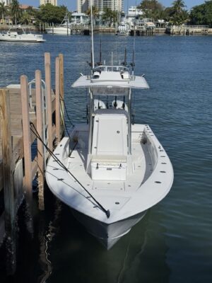 White center-console fishing boat at dock.